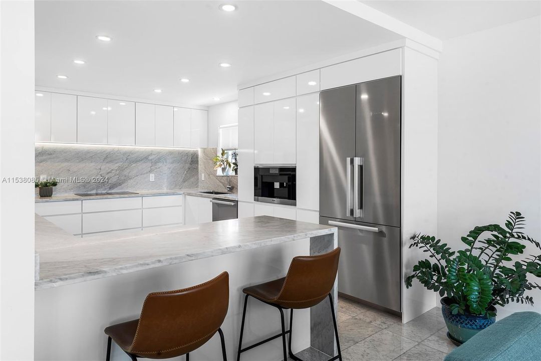 Remodeled open kitchen with Italian Carrara marble counters with waterfall edges