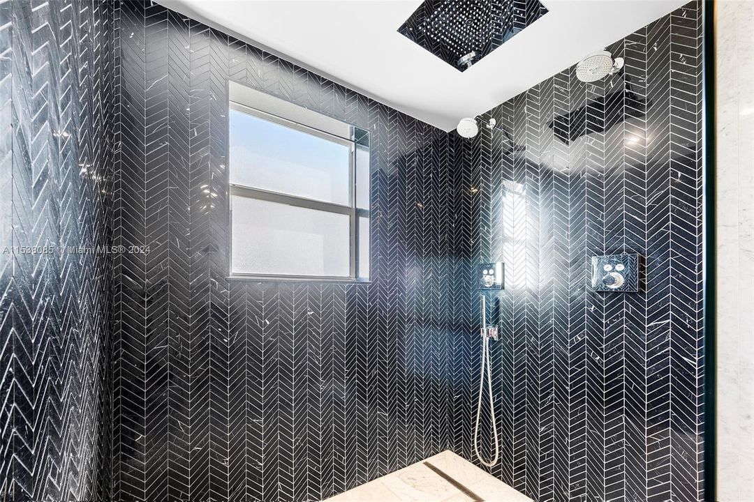 Oversized Nero Marquina marble shower with mega ceiling mounted rain shower, and dual Hansgrohe shower heads