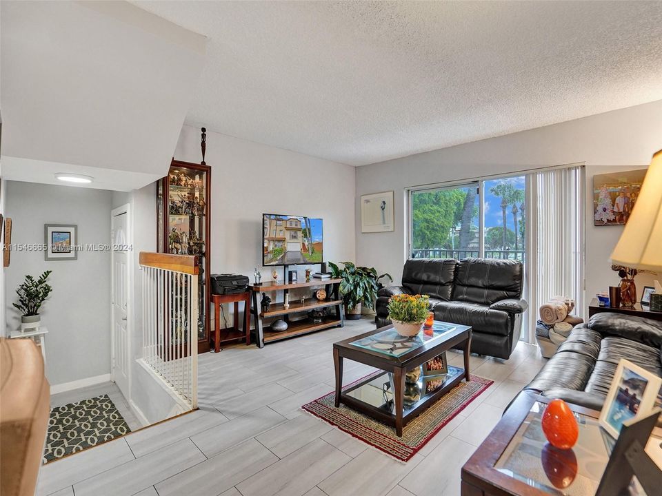 FOYER AND SPACIOUS LIVING ROOM WITH TOP-OF-THE-LINE CERAMIC FLOORS AND SLIDING GLASS DOORS