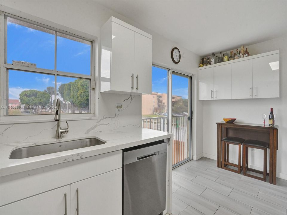 FULLY RENOVATED EAT-IN KITCHEN WITH WHITE CABINETS, QUARTZ COUNTERTOPS AND BACKSPLASHES, STAINLESS STEEL APPLIANCES, TOP-OF-THE-LINE CERAMIC FLOORS, BREAKFAST AREA AND LAKE VIEWS