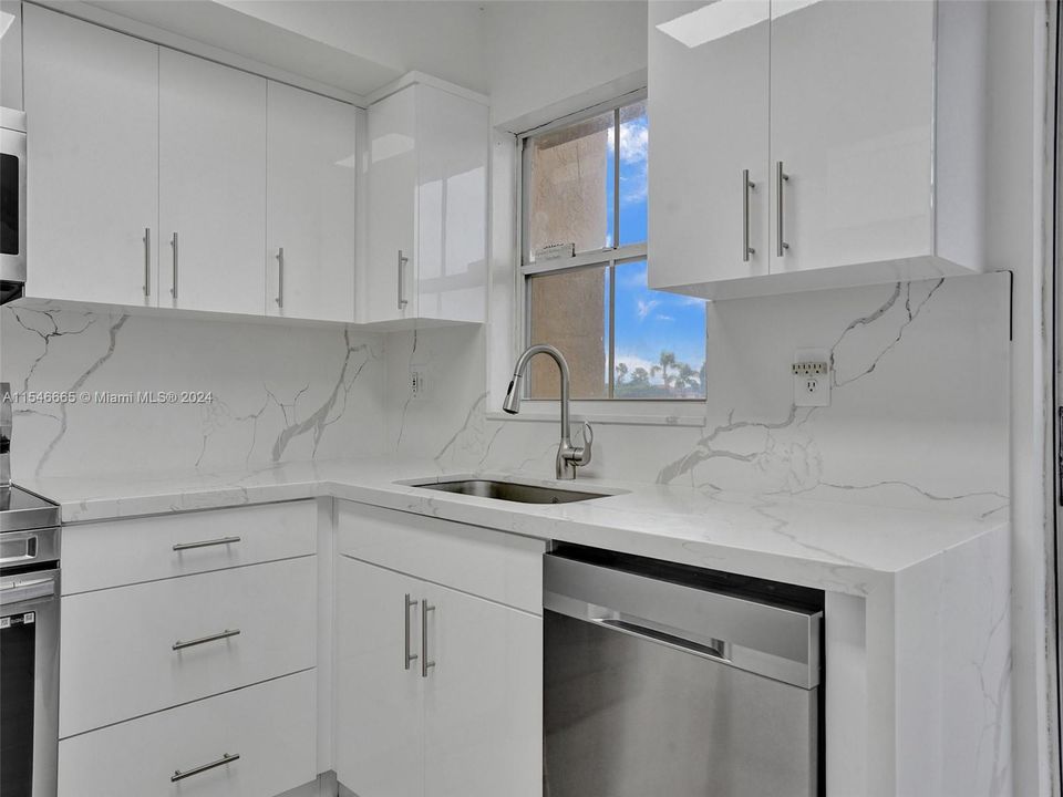 FULLY RENOVATED EAT-IN KITCHEN WITH WHITE CABINETS, QUARTZ COUNTERTOPS AND BACKSPLASHES, STAINLESS STEEL APPLIANCES, TOP-OF-THE-LINE CERAMIC FLOORS, BREAKFAST AREA, SLIDING GLASS DOORS, WINDOW AND LAKE VIEWS