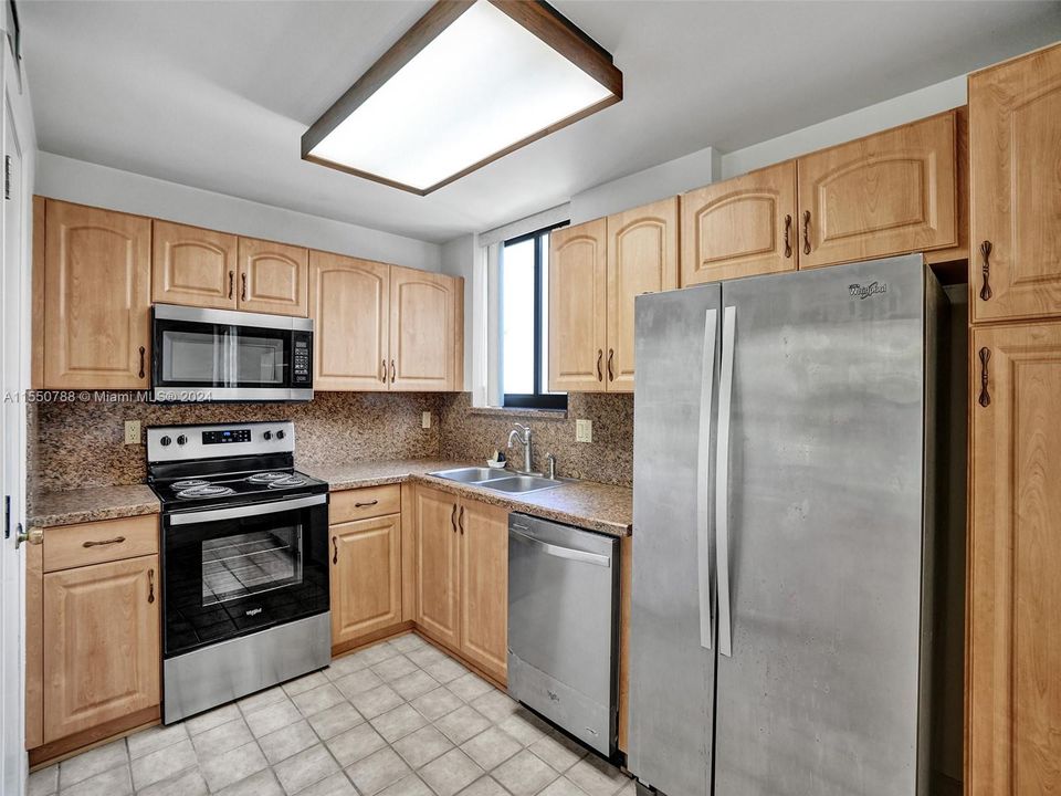 Stainless steel appliances with plenty of space, pantry, cabinet storage, and an abundance of counter top space for cooking & bar seating