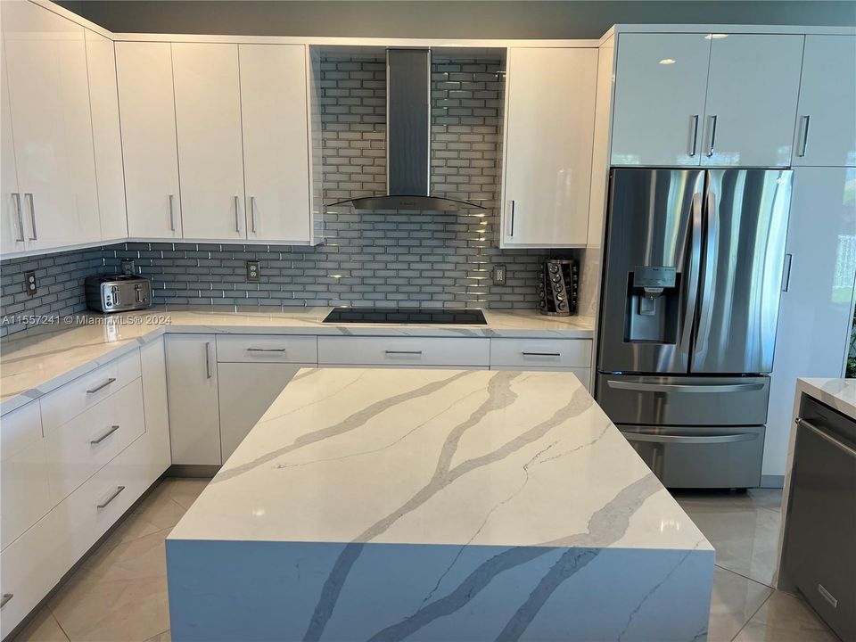 Amazing Hood over cook top with Glass subway tiles for back splash and built in Counter Depth Refrigerator!