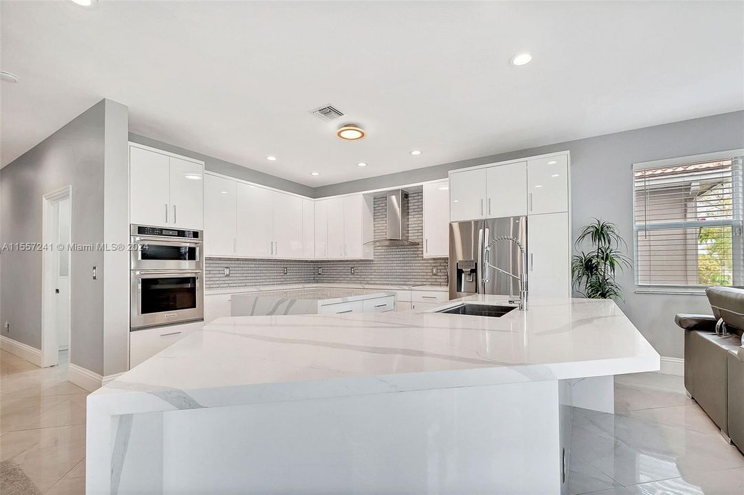 Brand new Contemporary Kitchen with white, high gloss Cabinets - Quartz Counters - and Stainless Steel Appliances! Check out this fabulous hood exhaust.