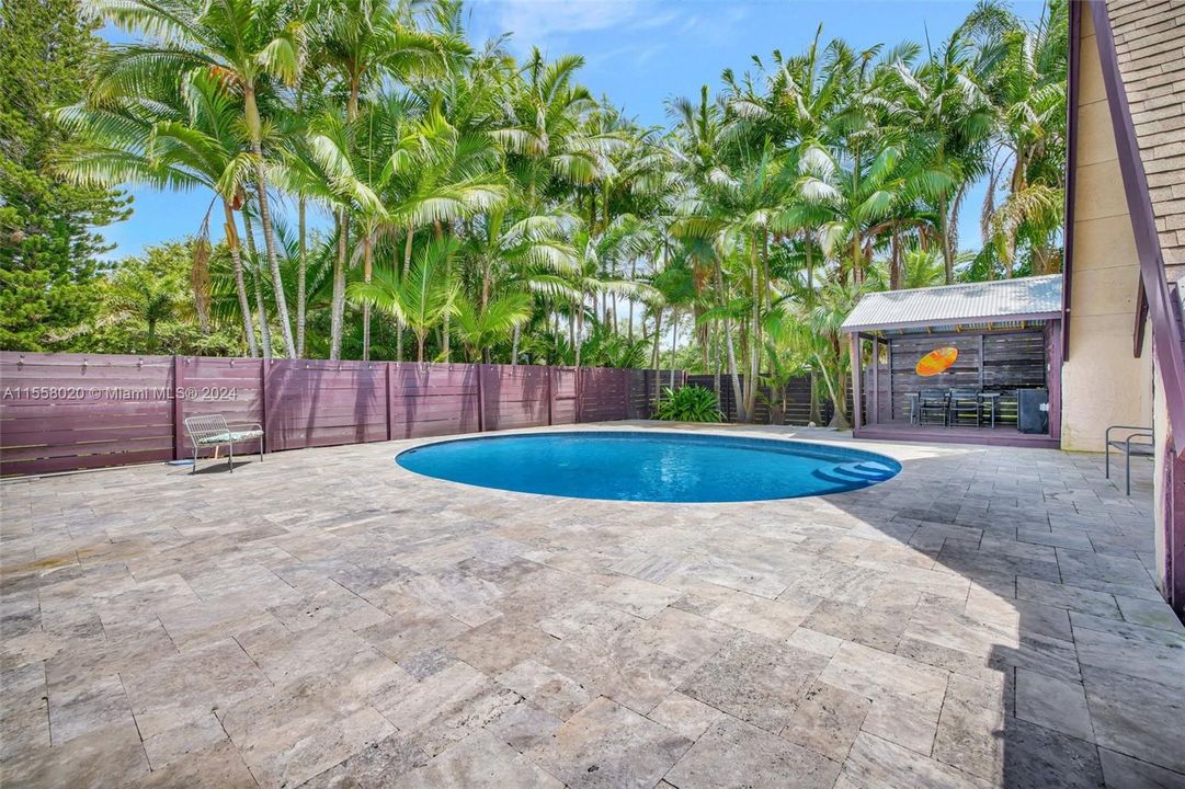 Travertine deck and resurfaced pool finish. Tropical palm tree garden backyard