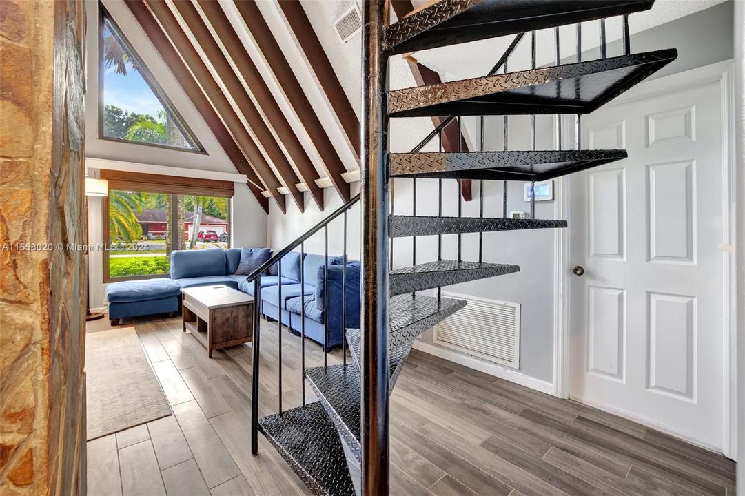 Spiral staircase leads up to primary bedroom and primary bathroom retreat