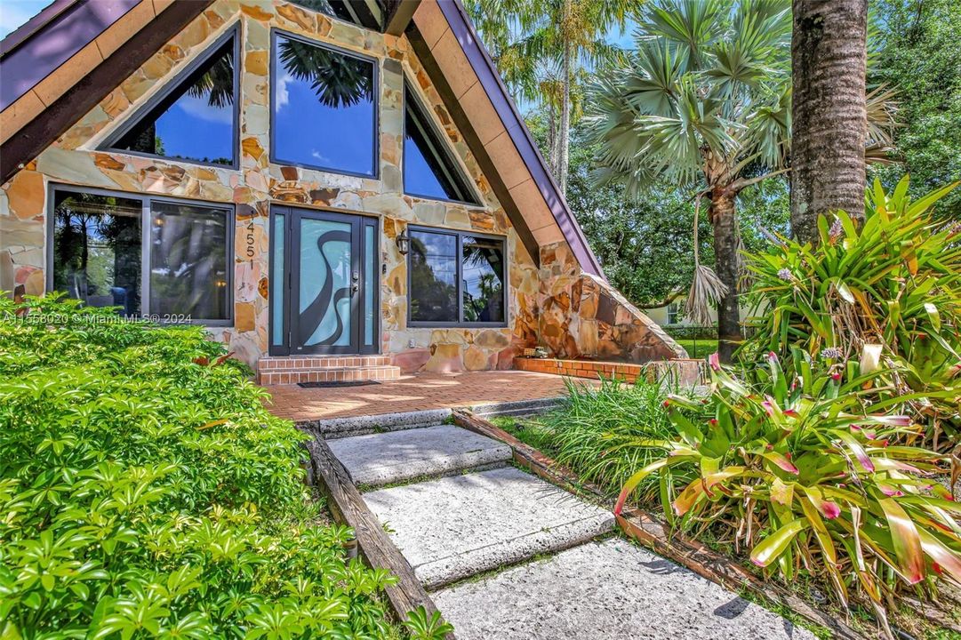 The architectural ingenuity of the A-frame design, the rustic charm of beamed ceilings, the timeless elegance of a natural stone fireplace, and the enchanting beauty of a tropical landscape come together in perfect harmony.