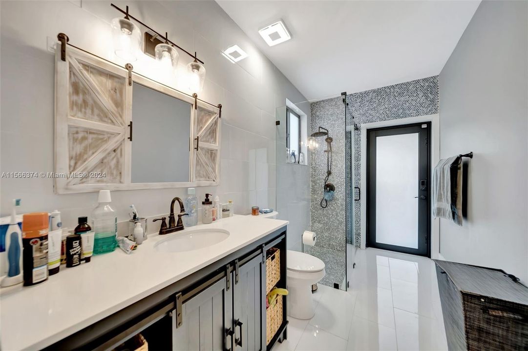Totally remodeled FULL downstairs bathroom with Custom tile and amazing vanity. The door leads to the yard. Perfect Cabana Bath!