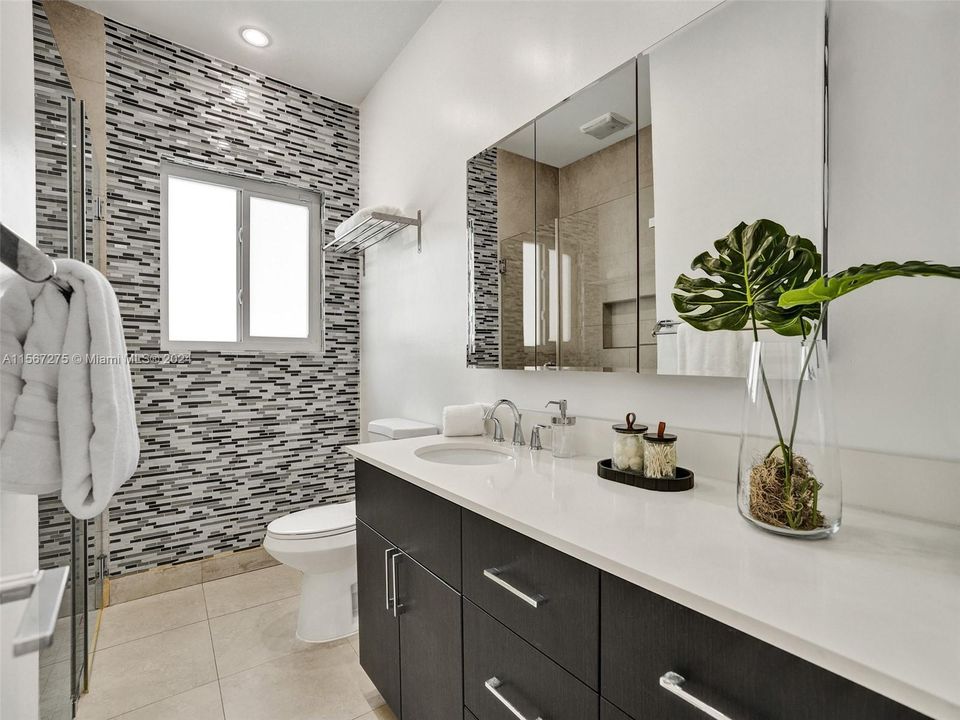 A full bathroom, complete with a tiled-in shower and glass door, serves as a central oasis between the two secondary bedrooms.