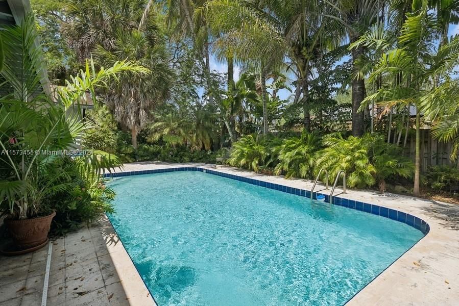 Pool is surrounded by tropical ferns, palms, trees and orchids