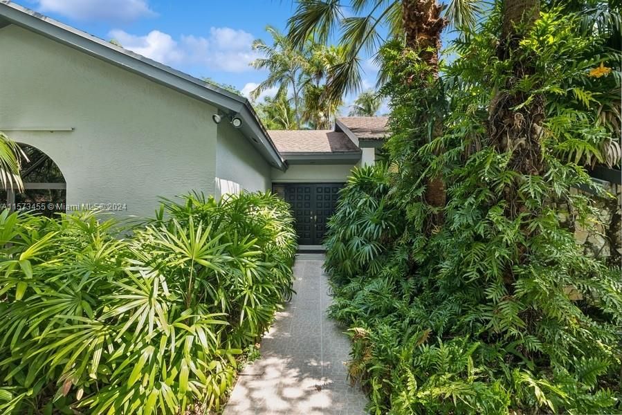 Ferns and palms adorn the front walkway entrance