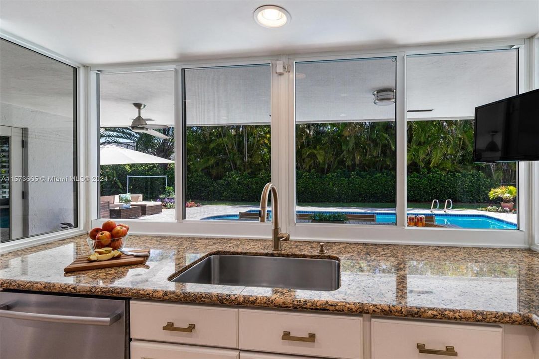 Large counter near kitchen sink adds to functionality as well as the pass-through to the covered patio and pool area
