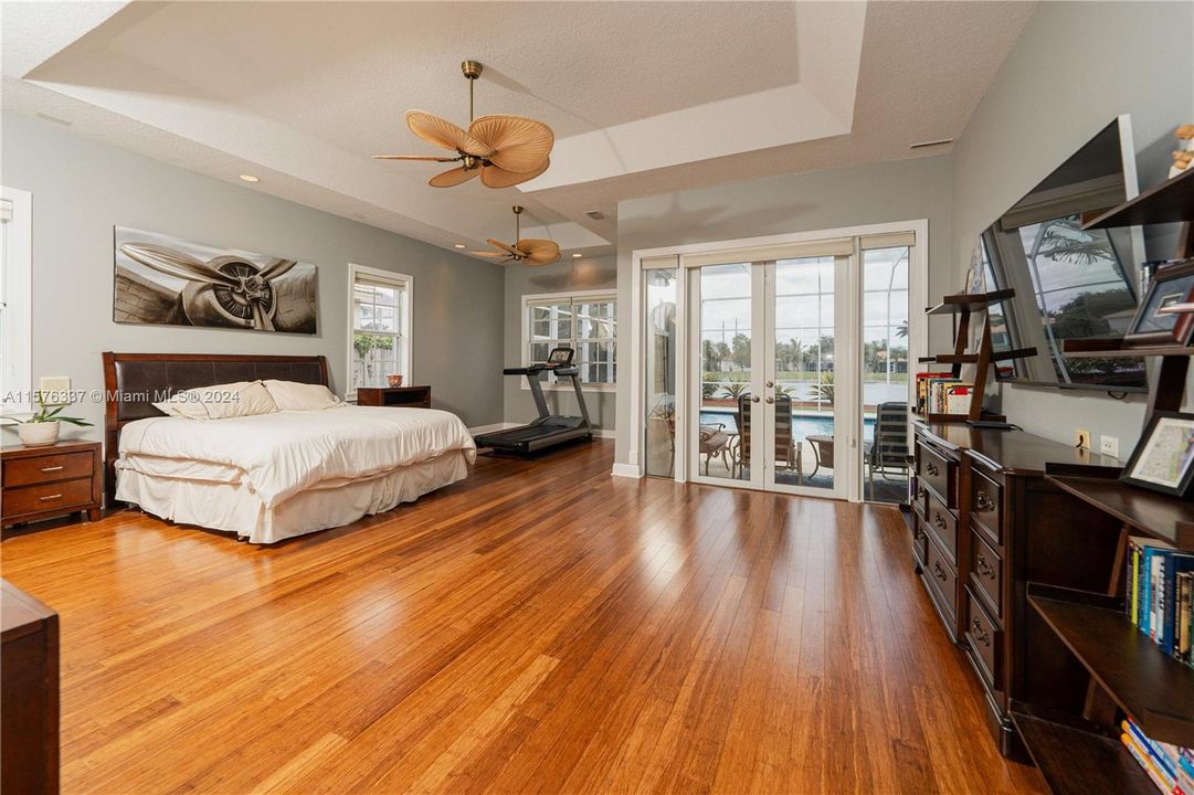 Spacious primary bedroom with french doors leading to the pool