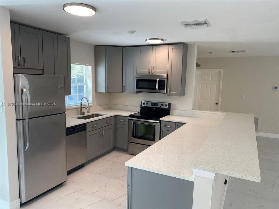 stainless steel appliances, gray cabinetry, granite.