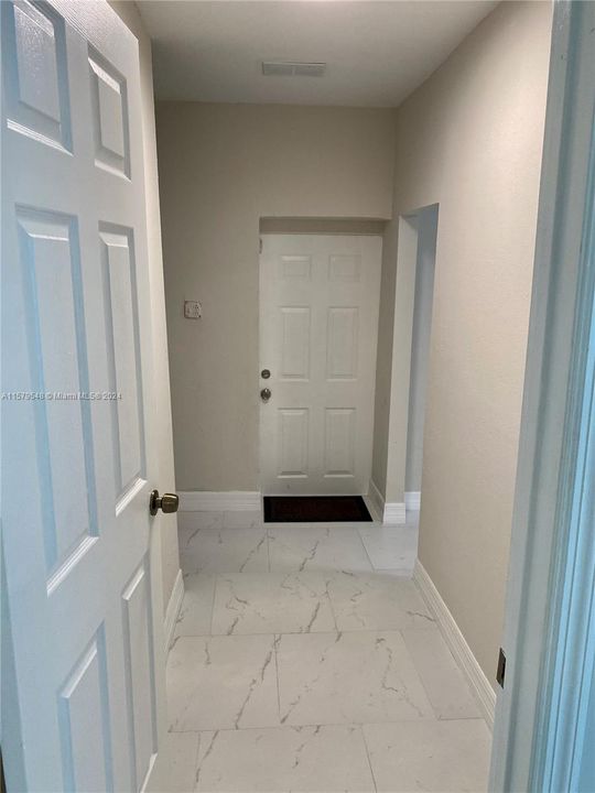 hallway that accesses the additional space on the right and the laundry area on the left. Access to the side of the house can be gained through the door at the end.