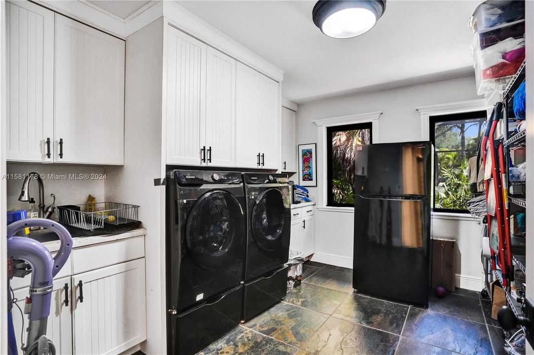 Step into a laundry room that seamlessly combines practicality with convenience, featuring the added luxury of a second fridge. Nestled within this functional space, sleek appliances and ample storage solutions await, ready to streamline household chores with effortless efficiency