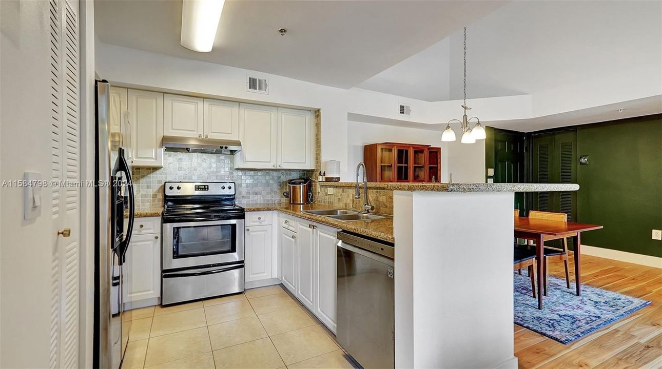 Updated kitchen with granite countertops, tiled backsplash, SS appliances opens to dining area with soaring ceilings in this exclusive top-floor corner unit.