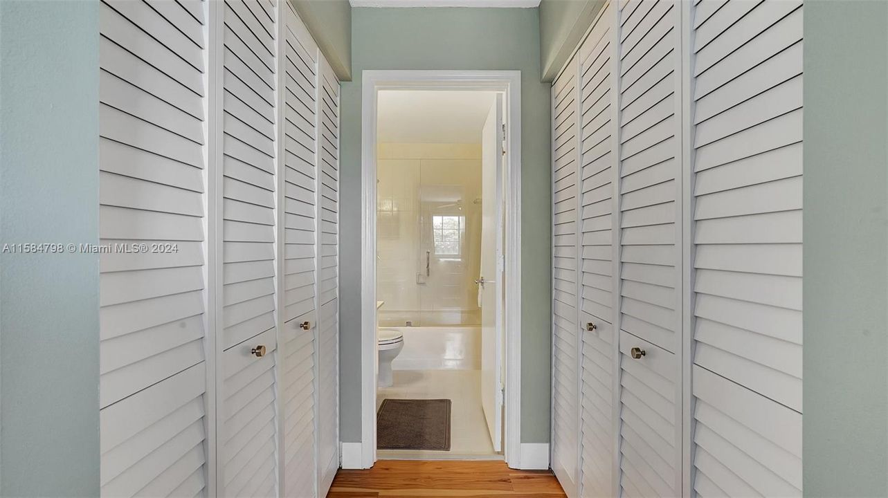 Hallway lined with closets leading to updated en-suite bath.