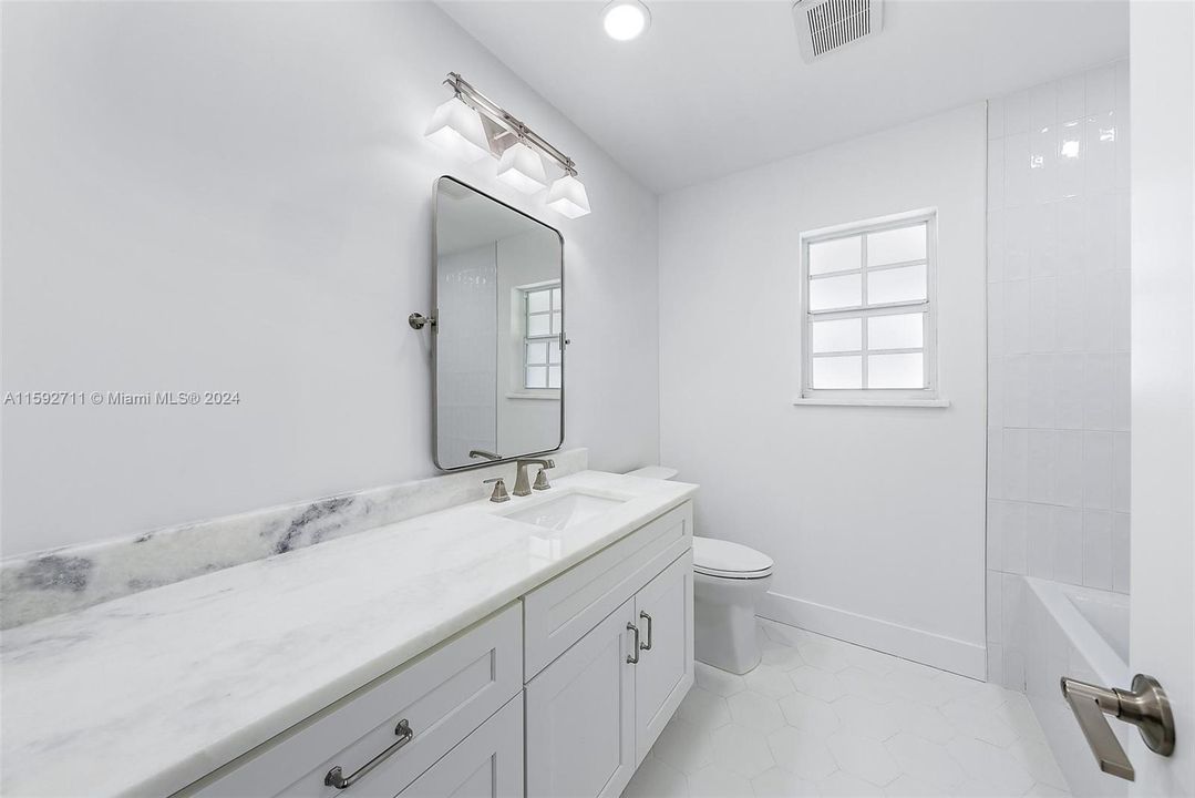 Guest Bathroom with new Swiss White Marble countertop, cabinetry, all new tile and lighting, shower/tub combo.