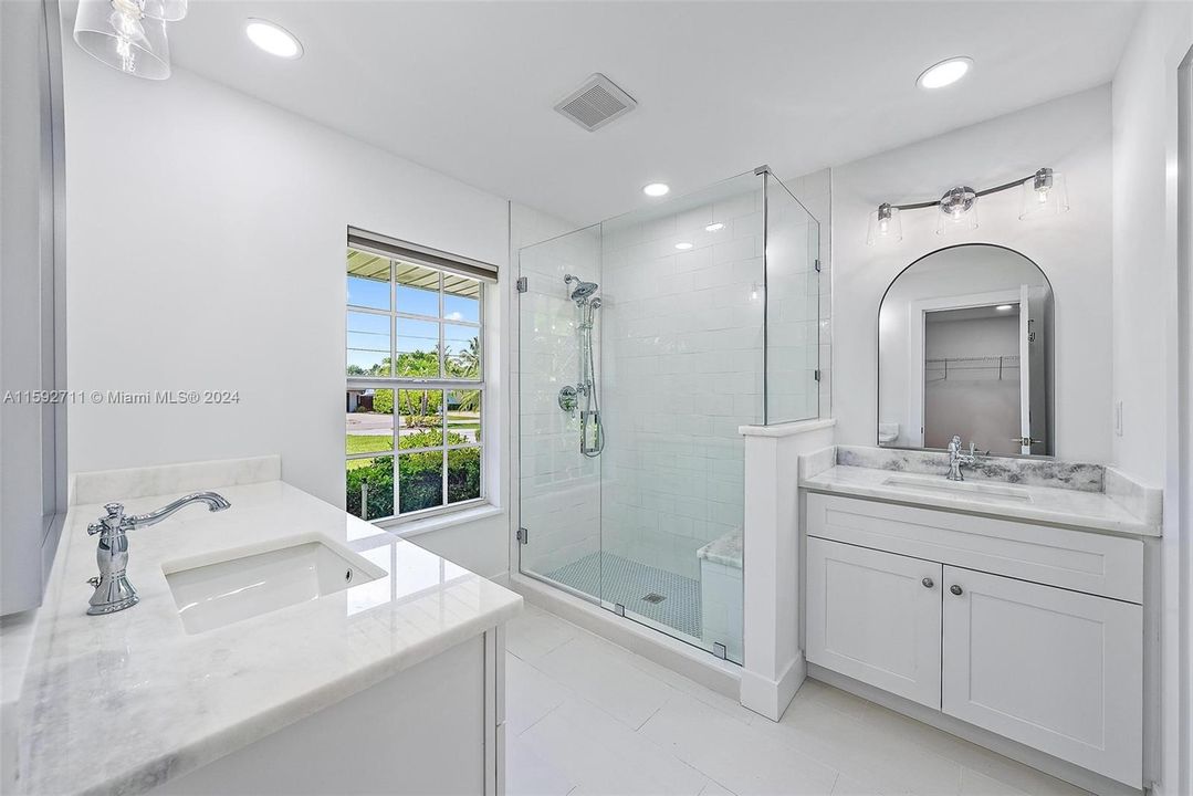 Primary Bathroom all new vanities with Swiss White Marble countertops, all new tile, lighting and fixtures.