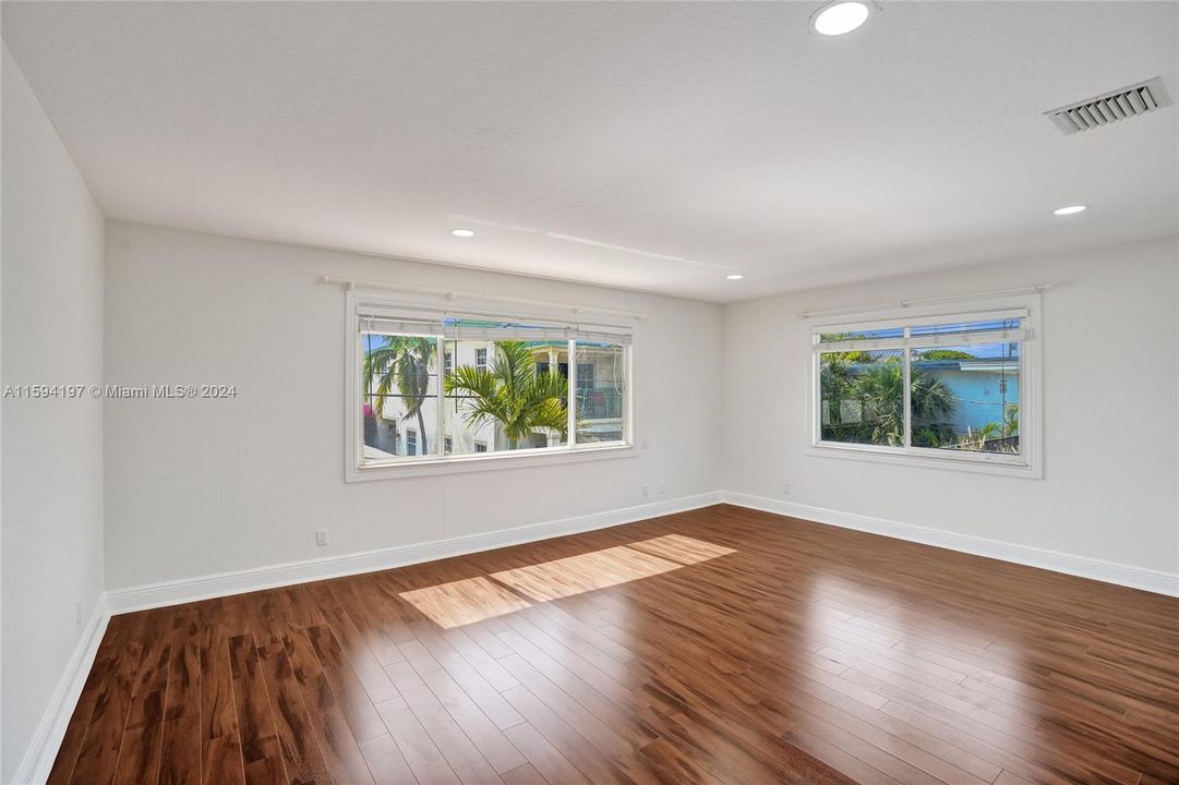 Spaciouse primary bedroom with wood floor and lots of natural light.