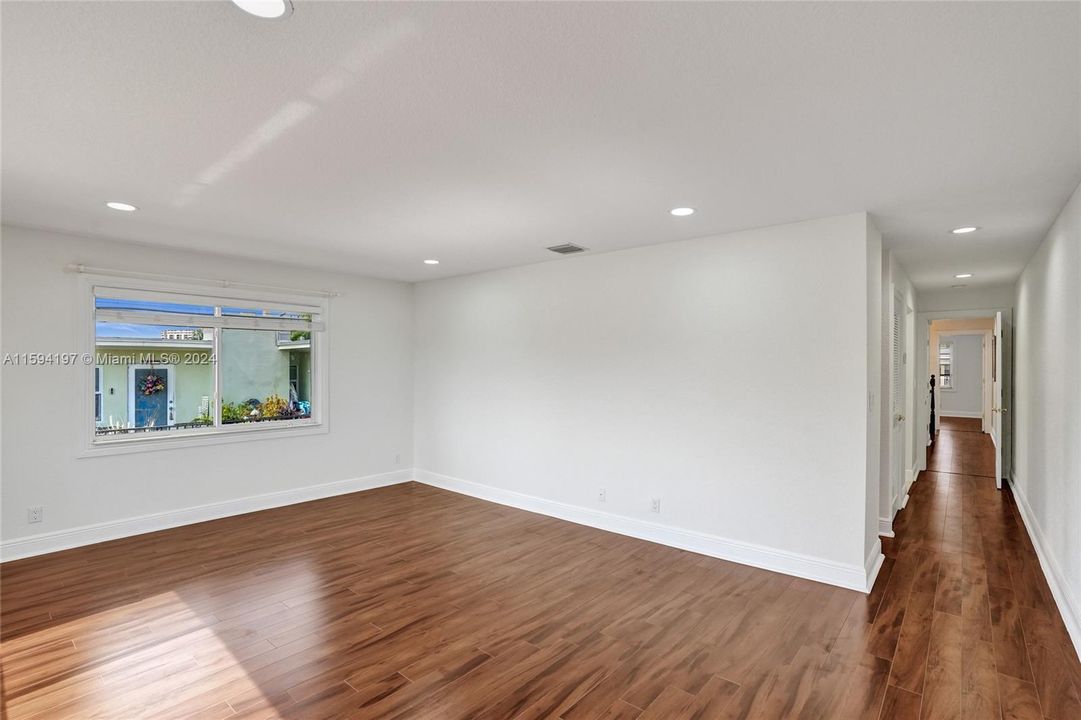 Spaciouse primary bedroom with wood floor and lots of natural light.