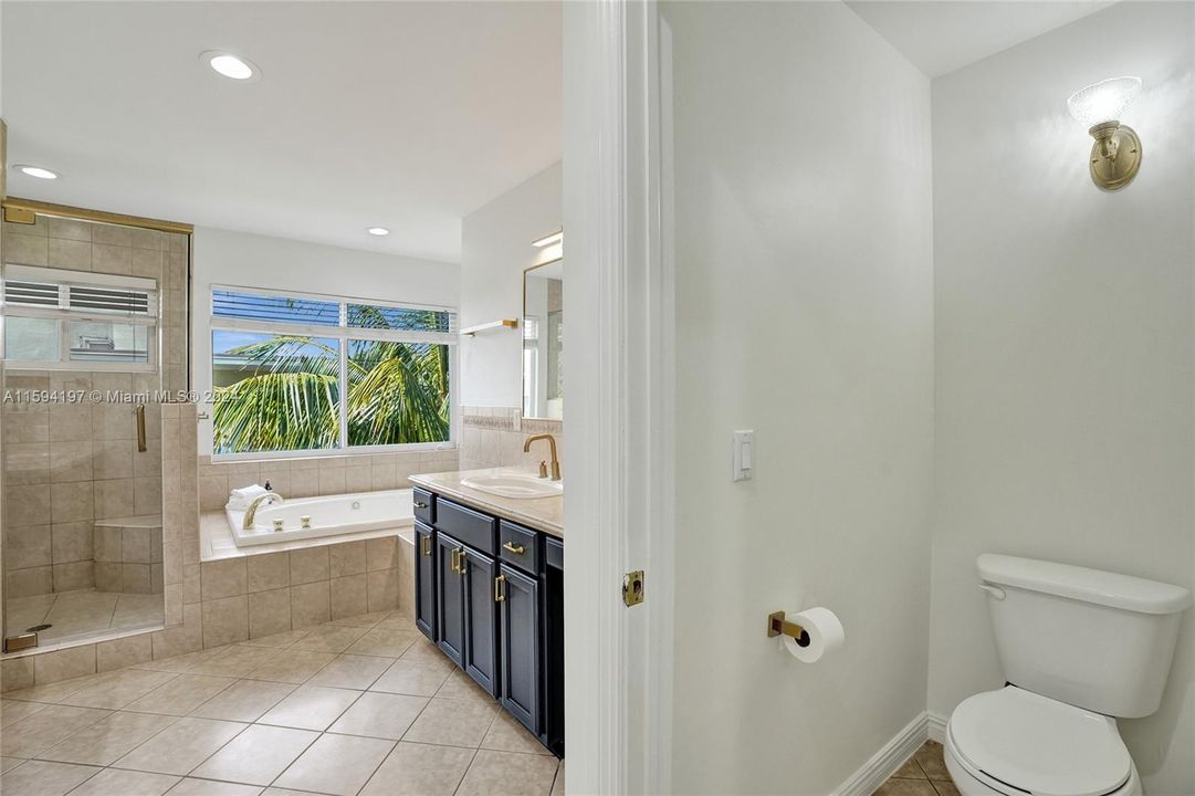 Primary bathroom with his and hers side, stand alone shower and roman tub and separate
