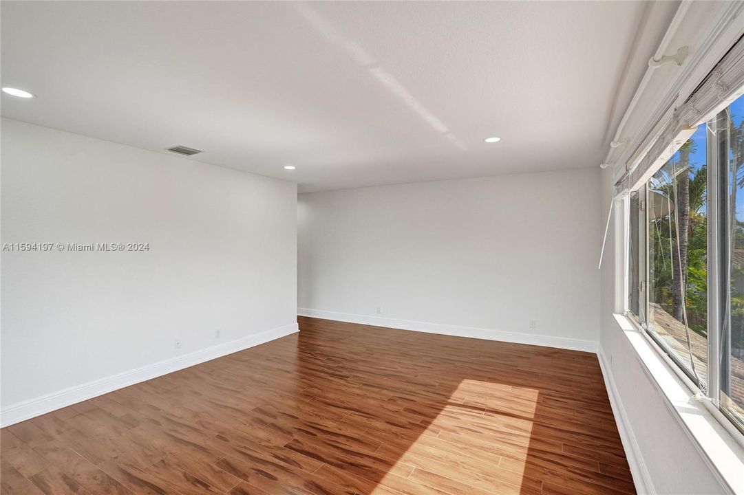 Spaciouse primary bedroom with wood floor and lots of natural light.