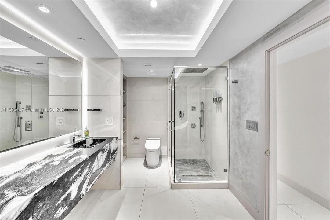 PRIMARY SPA LIKE BATHROOM WITH CUSTOM STONE COUNTERTOP, PLENTY OF STORAGE AND LARGE SHOWER