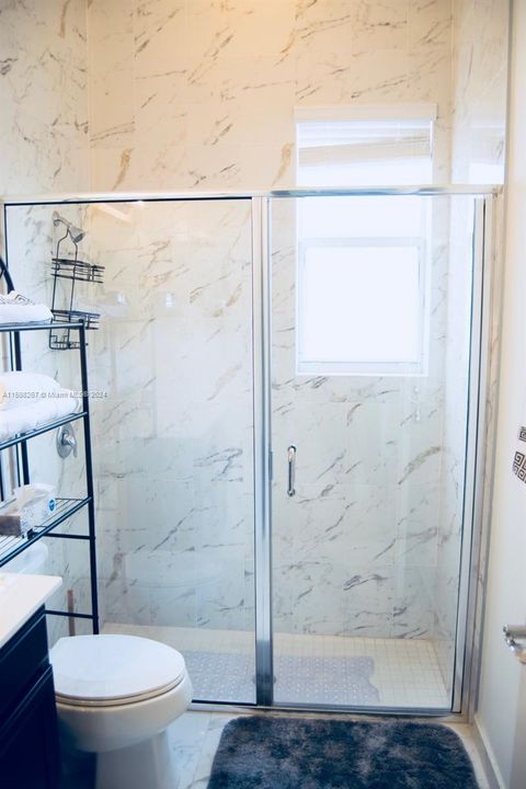The second bathroom features a standing shower with elegant glass doors.