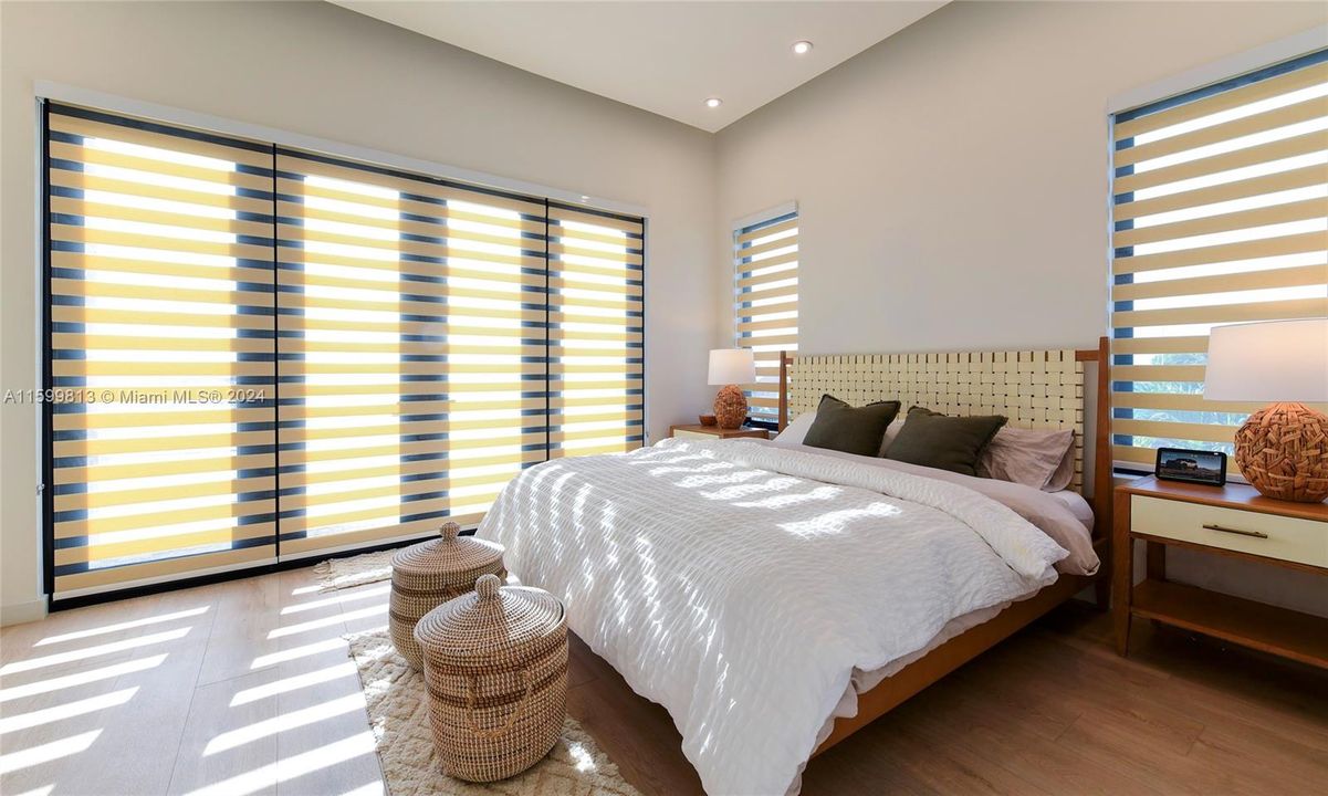 Primary Bedroom: Wake up to gentle sunlight streaming through stylish electric window treatments in this cozy, inviting bedroom. The neutral tones and soft bedding create a perfect retreat for relaxation.