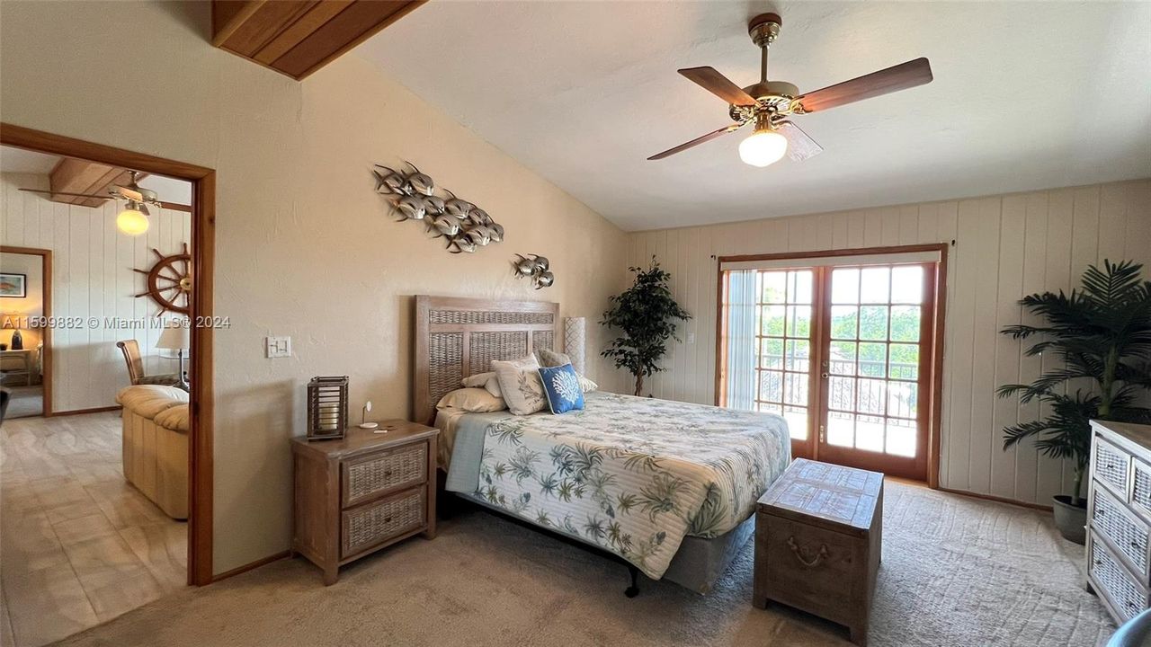 The spacious master bedroom offers a serene retreat with charming coastal decor, and direct access to a private balcony. Large windows and a ceiling fan ensure comfort and tranquility.