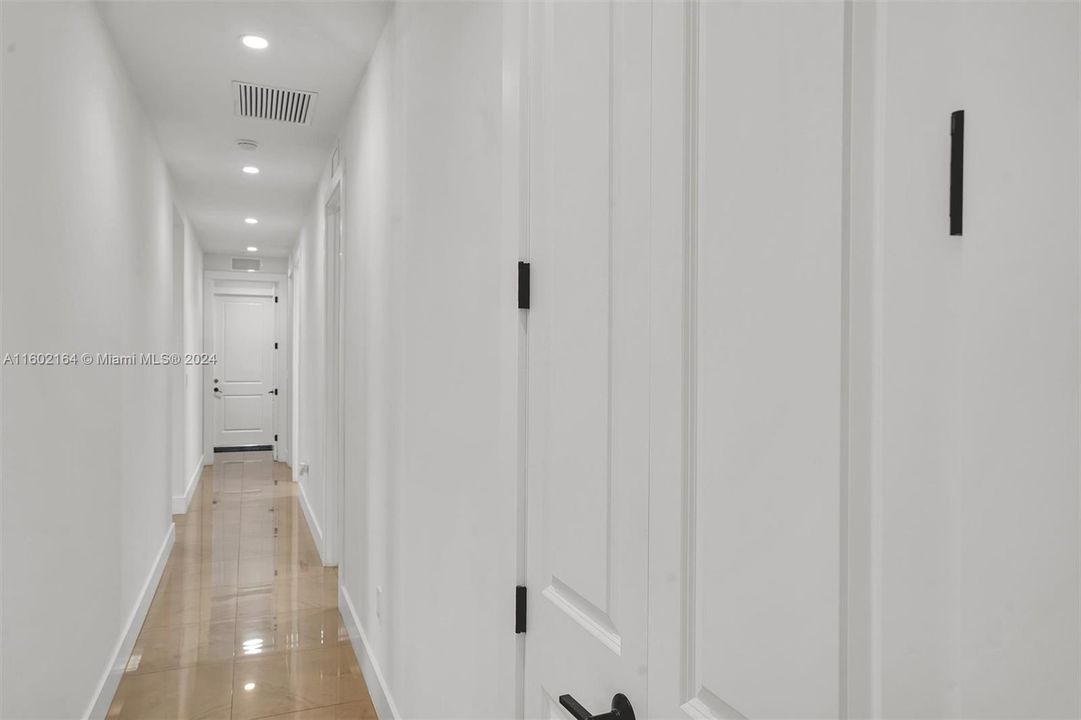Hallway with three bedrooms, one bath and laundry room at far end