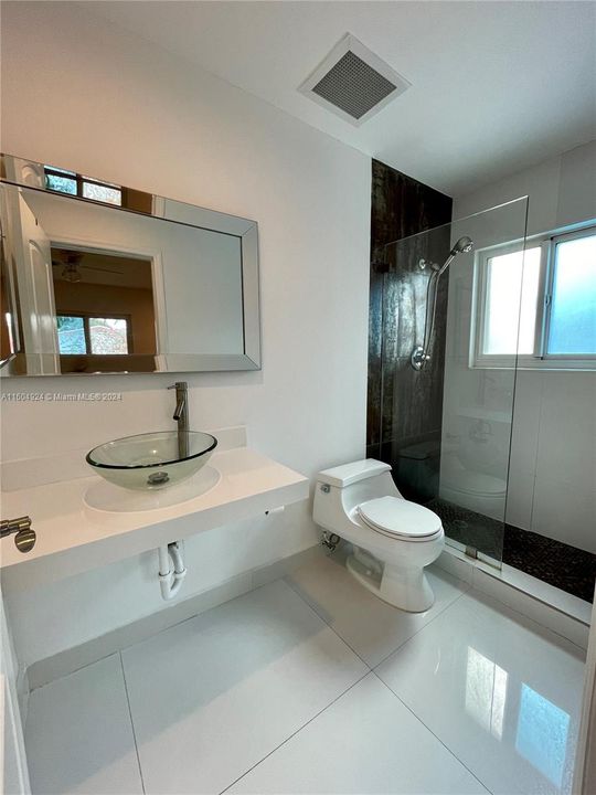 Remodeled master bathroom with beautiful porcelain floor and frameless shower door