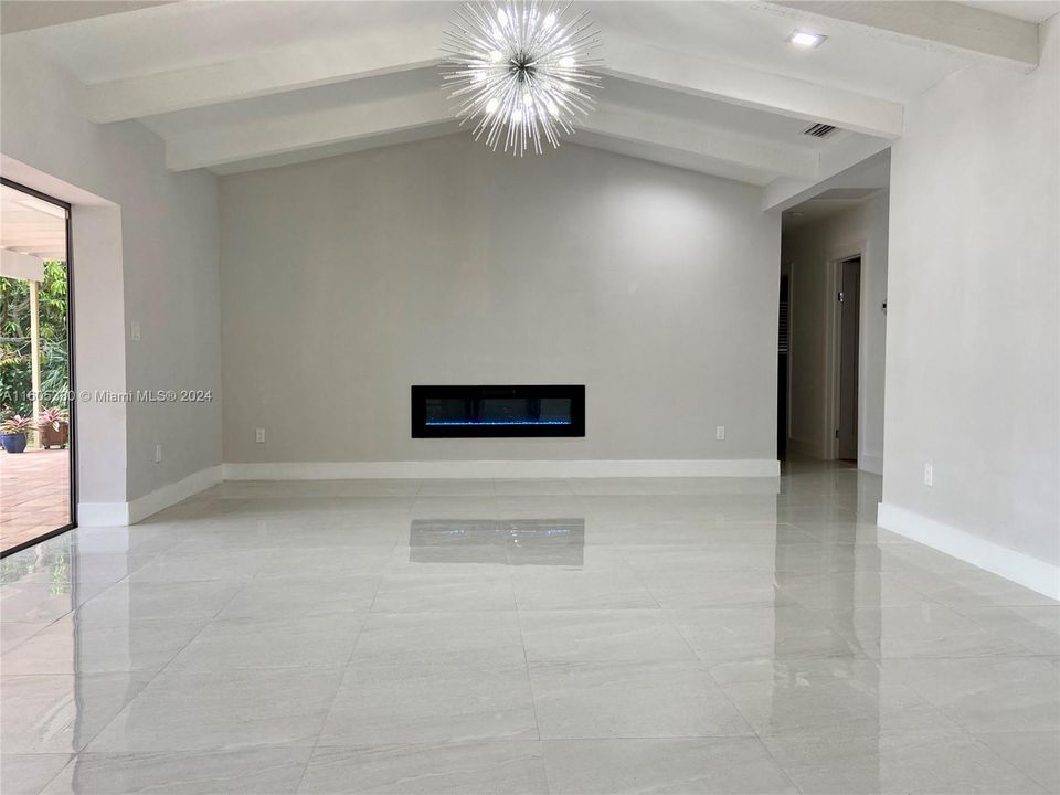 Family room with volume ceilings and LED fireplace overlooking the tropical gardens and pool.