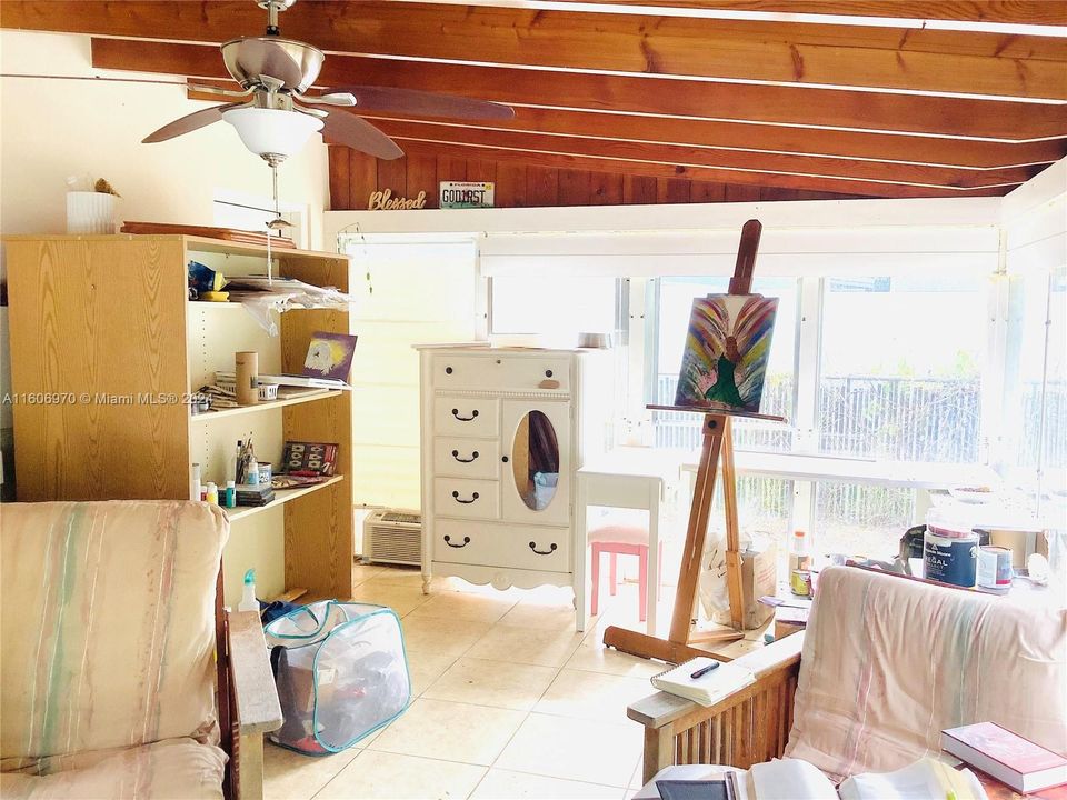 Enclosed back porch with fixed glass windows used as an artist’s studio