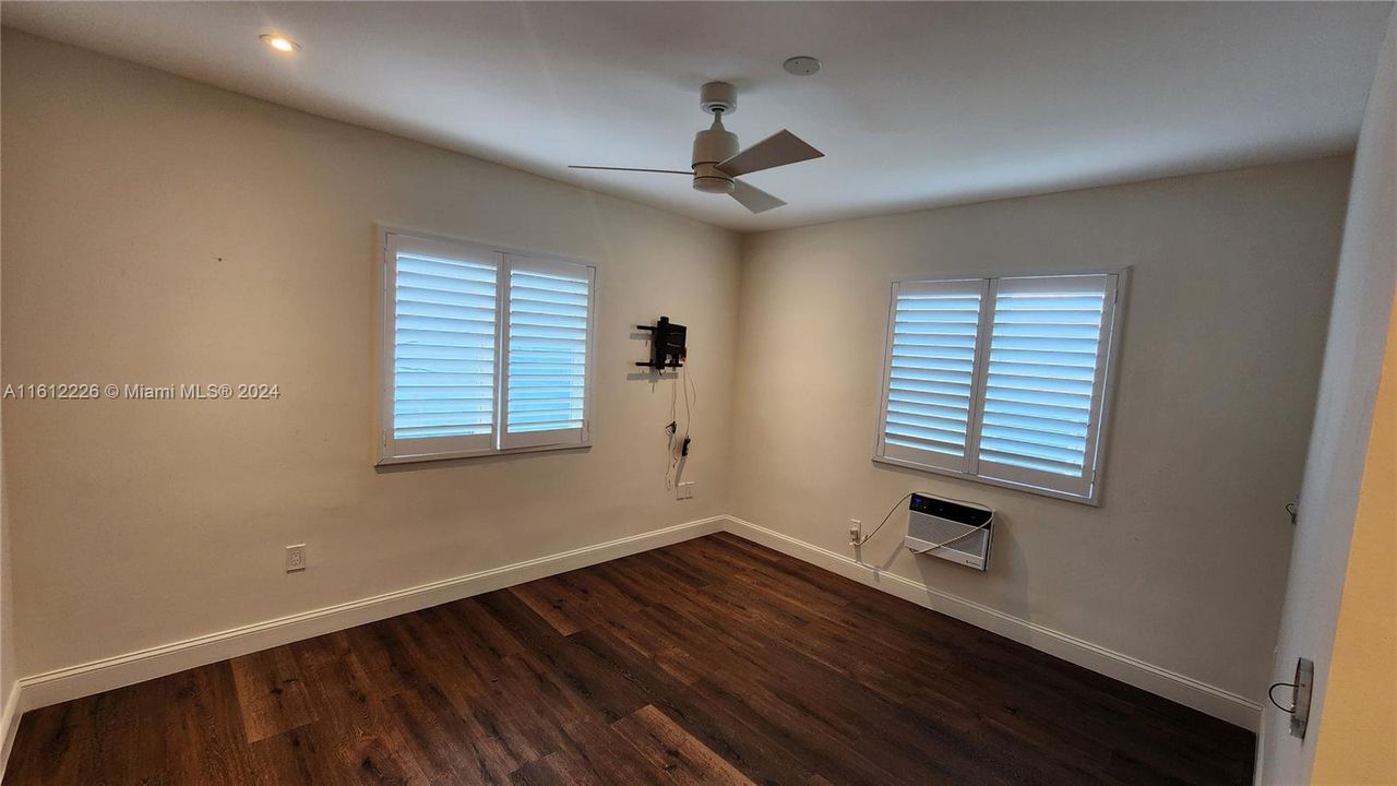 Spacious Bedroom with modern adjustable lighting, new wall A/C unit, new impact windows and fan.