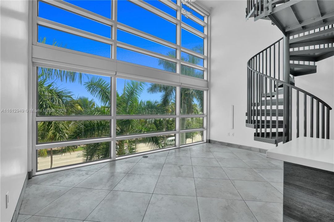 Double-height ceiling loft with modern kitchen, stainless steel appliances, spiral staircase, and mezzanine level. Bright, airy, and perfect for relaxation or entertainment.