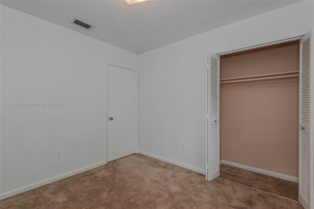 The 1st bedroom with the open closet and entry door.