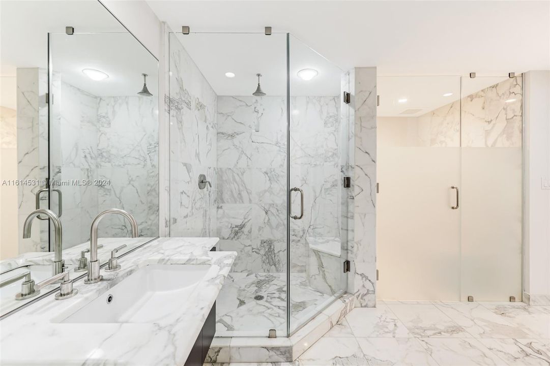 Primary bathroom with dual sinks, glass shower and water closet with toilet and bidet.