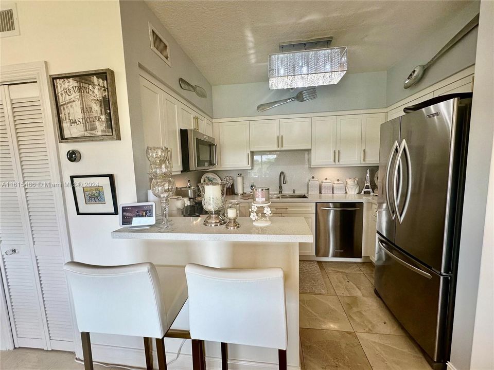 UPGRADED EAT-IN KITCHEN WITH WOOD CABINETS, QUARTZ COUNTERTOPS AND STAINLESS STEEL APPLIANCES