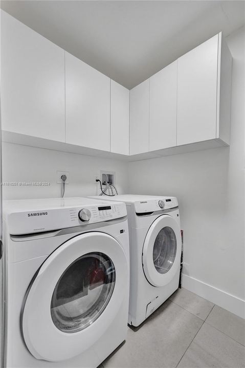 Separate laundry room with cabinetry.