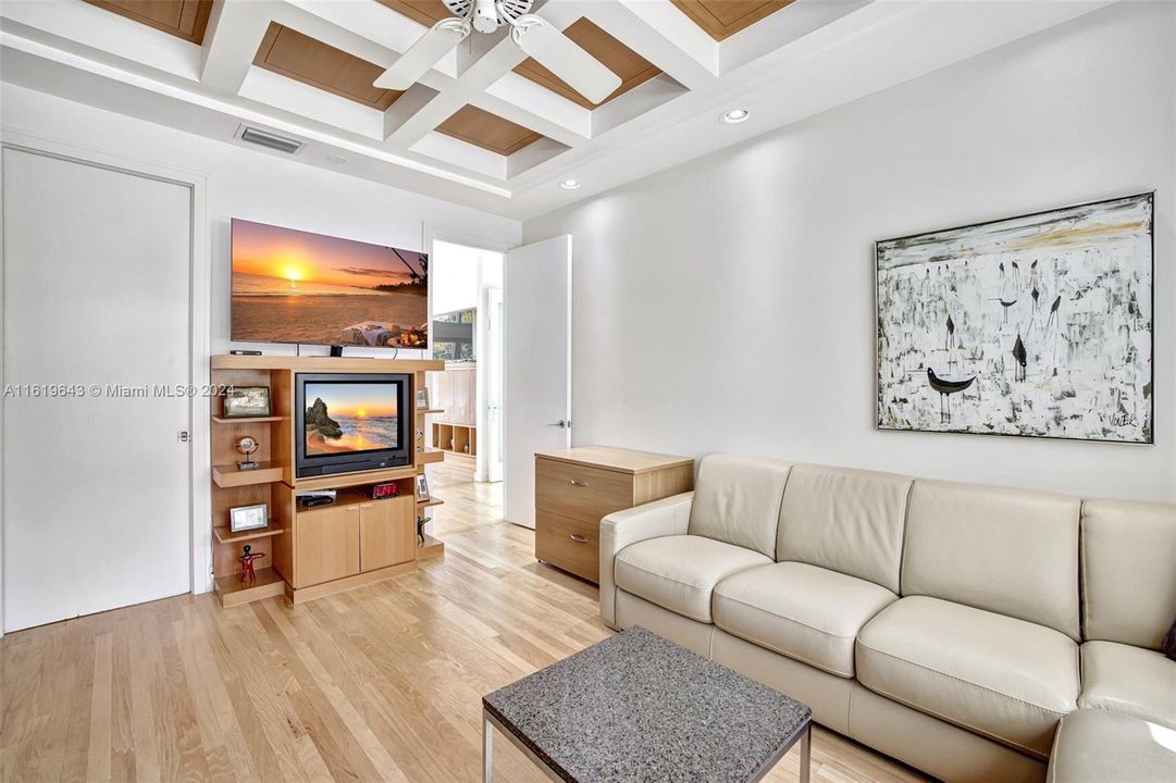 Cozy bespoke home office, accessible from the primary bedroom, features custom wood built-ins and coffered ceiling with wood inlay.