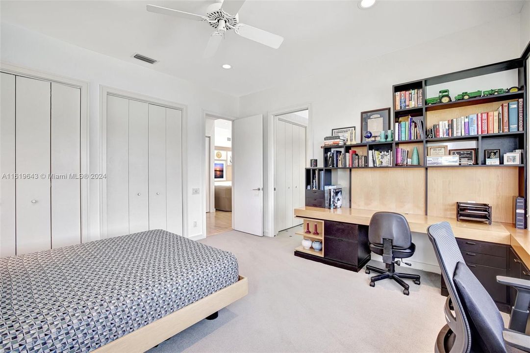 Guest bedroom w/ gorgeous water views, double custom closets, mirrored door and en suite bathroom. The bedroom features generous storage with the custom wrap-around built in shelving and desk space.