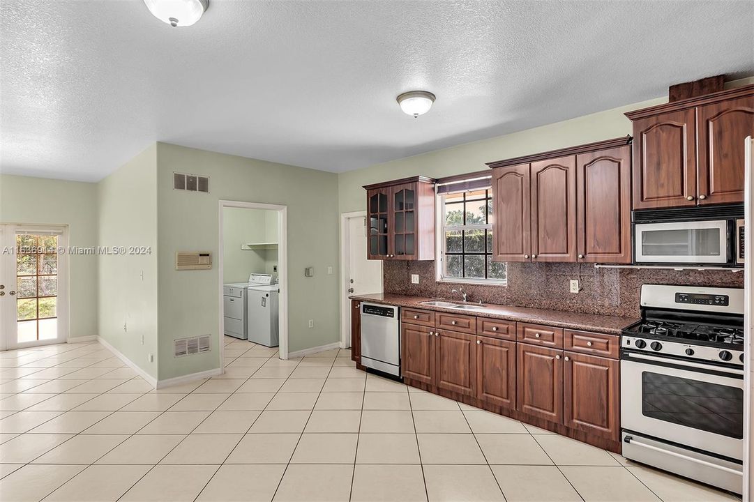 Ample kitchen, with granite counters, gas range, and large pantry.