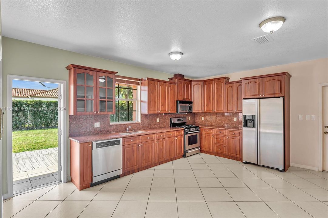 Ample kitchen, with granite counters, gas range, and large pantry.