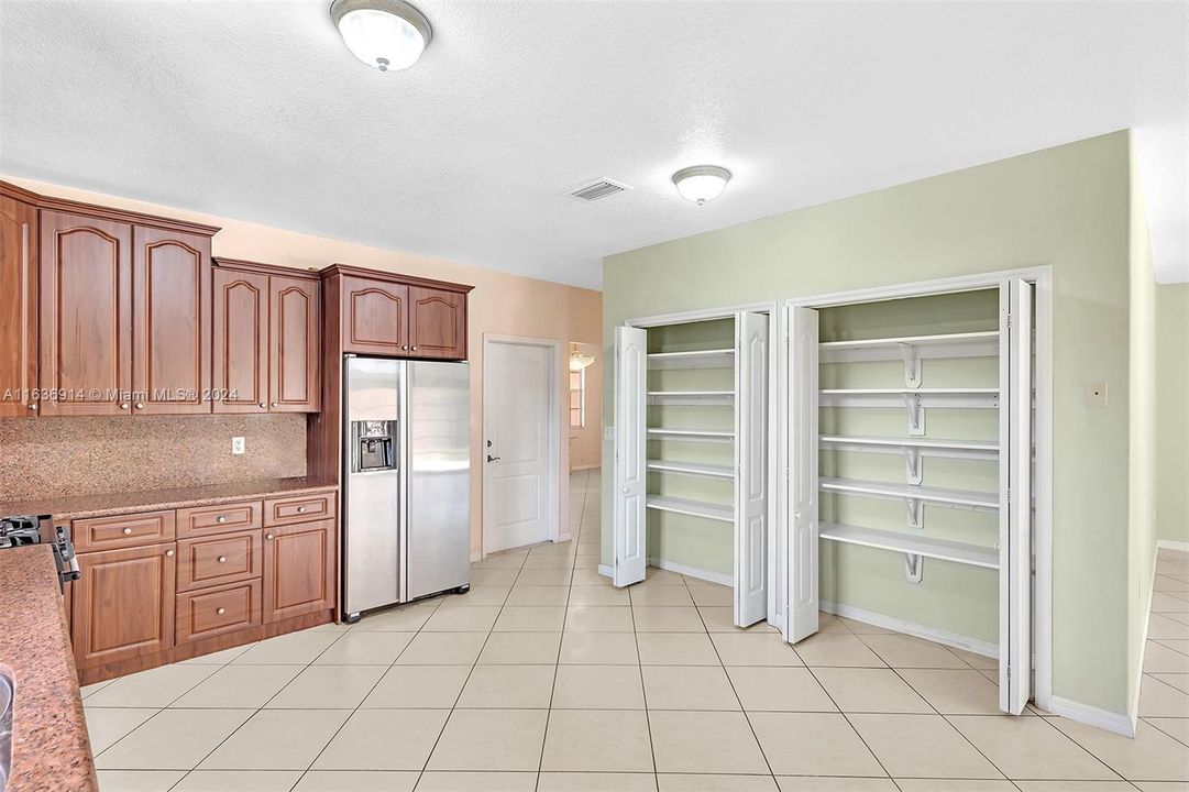 Ample kitchen, with granite counters, gas range, and large pantry.