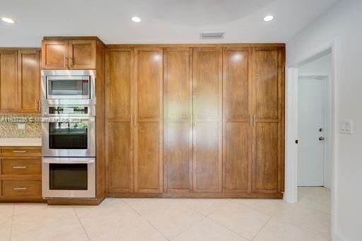 LG stainless steel double ovens and microwave, with custom wood cabinetry featuring wall to wall panty in the kitchen eat in area.