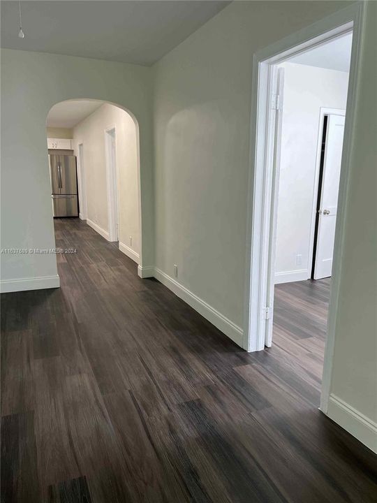 Main living area facing 1st bedroom ddor and arched hallway to kitchen, bath, bedrooms