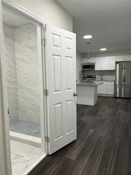 Hallway entrance to bathroom with view to kitchen.
